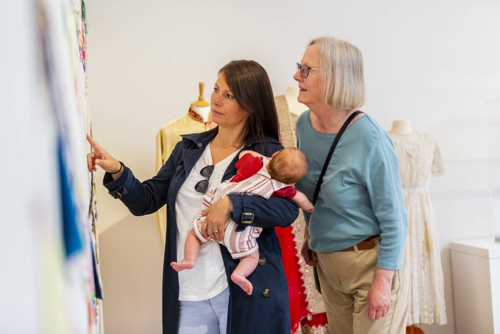 Skipton Town Hall_168 Two women look at the gallery display. One of them is holding a baby.