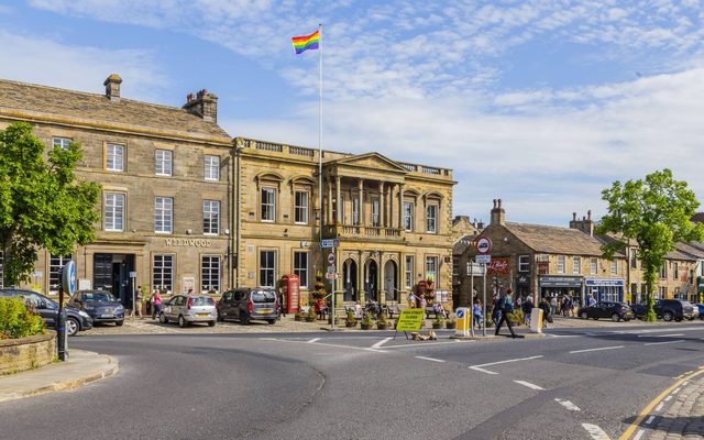An exterior view of Skipton Town Hall with a rainbow pride flag flying on the flagpole.