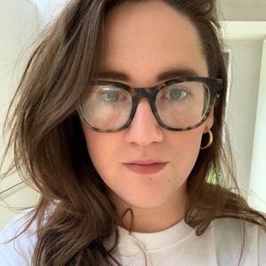 Megan Woman with long dark hair, white tshirt and glasses.