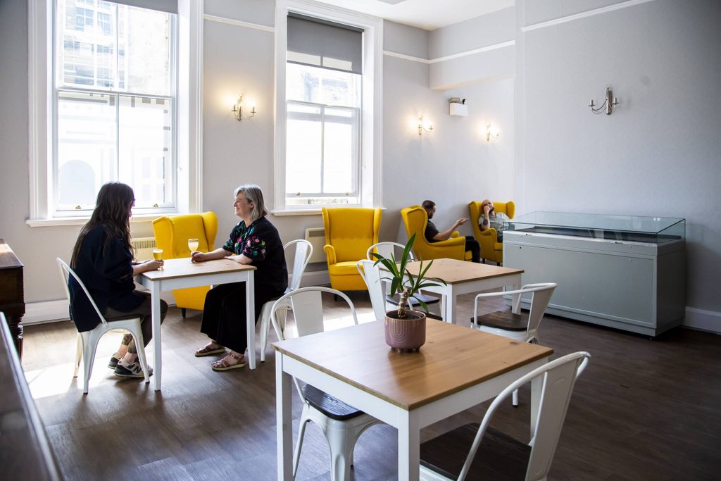 The Hub room with two women sat at a table with drinks.