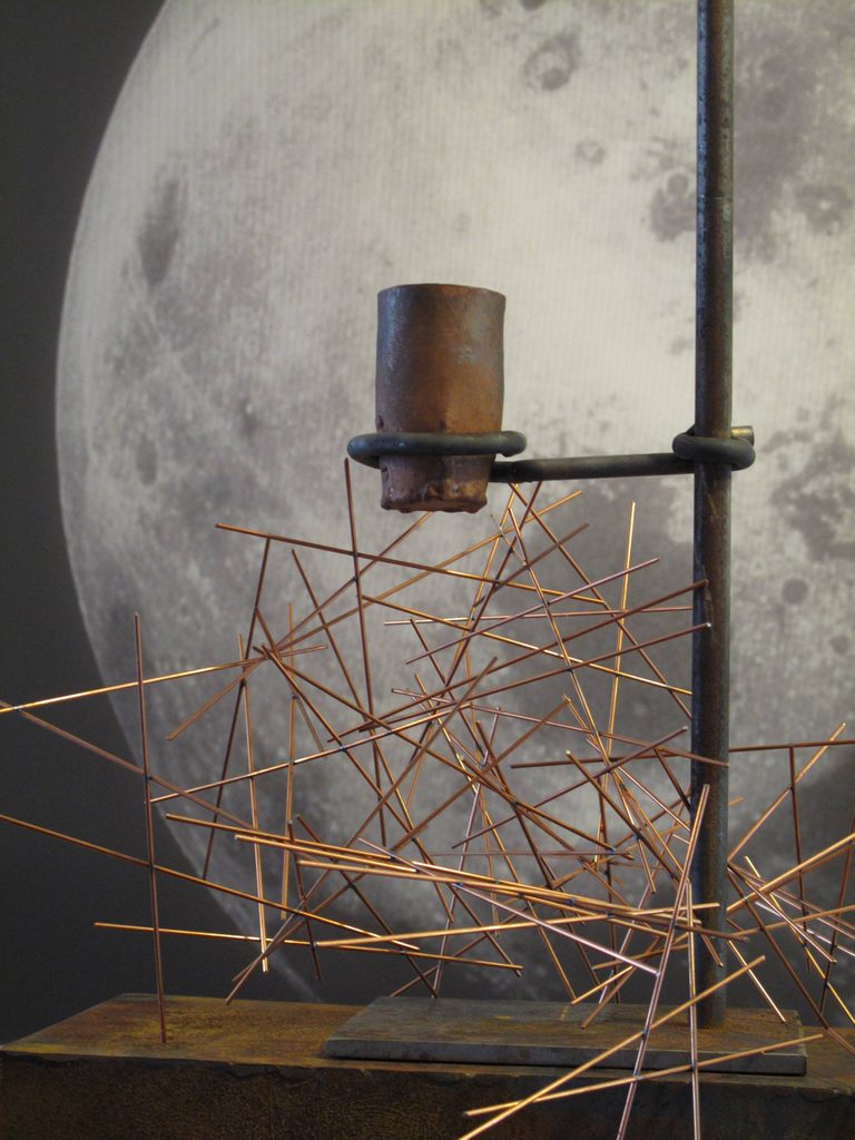 Sculpture with copper rods and image of the moon in the background