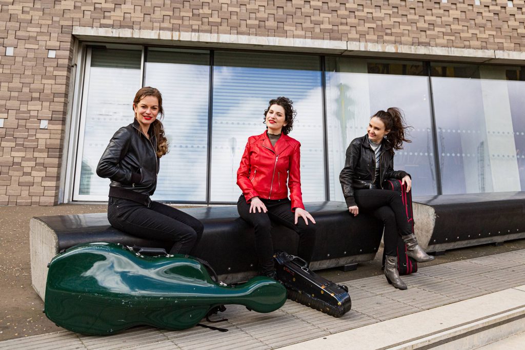 Three women with string instruments in cases