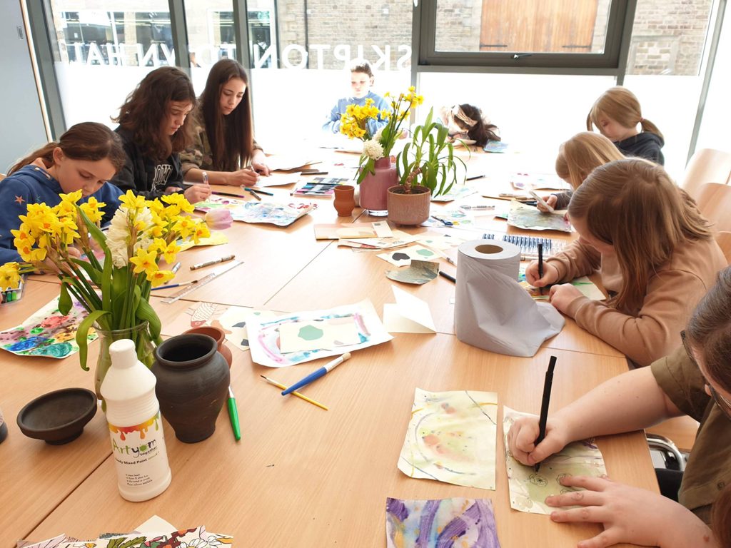 Art Club 01 A group pf young people sit round a table . they are drawing.