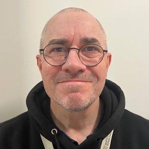 Stuart A man with very short hair and glasses