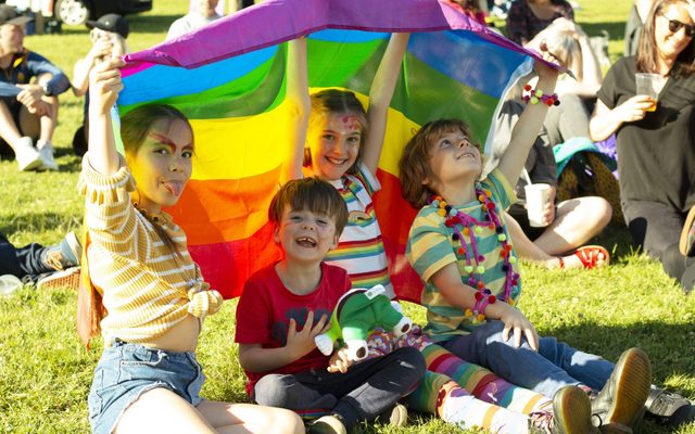 Four children holding up a rainbow pride flag